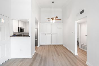 A modern kitchen with white cabinets and a wooden floor.